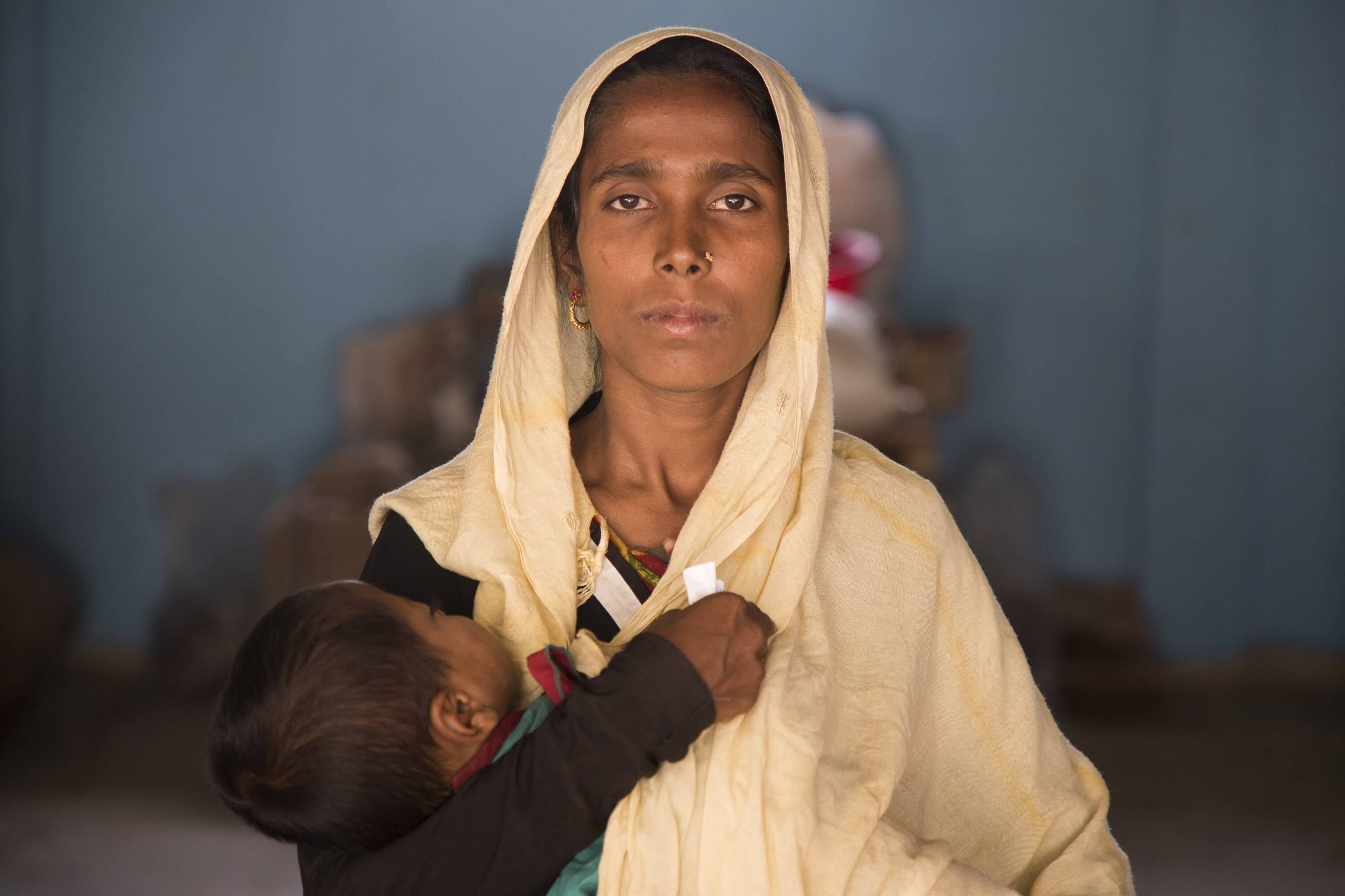 Aseya holds her 2-year-old child. Her husband is disabled and she provides for her family.