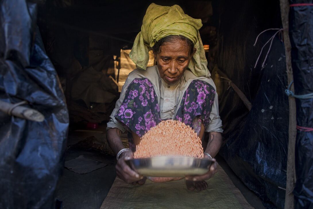 An elderly woman in the camp is busy preparing a meal for her family with the food ration she received